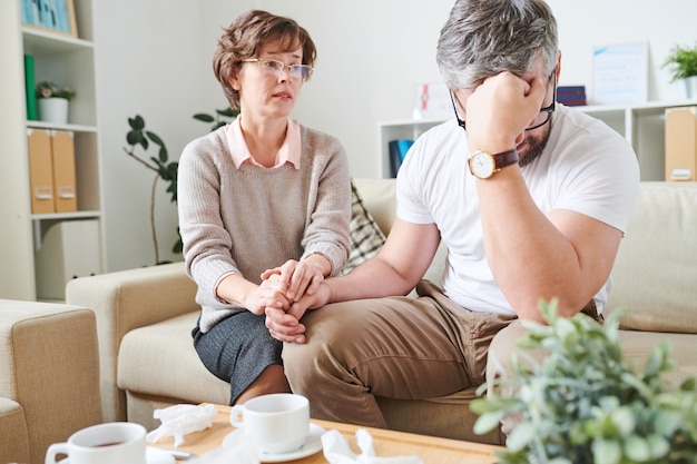 Verzweifelter Mann, der mit Emotionen während der Therapiesitzung fertig wird