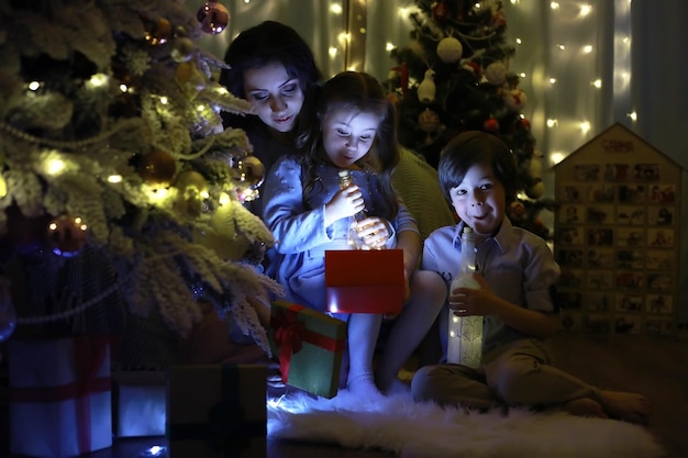 Foto véspera de ano novo. a casa está decorada para o feriado. árvore de natal elegantemente vestida com uma guirlanda e uma família com presentes e uma surpresa.