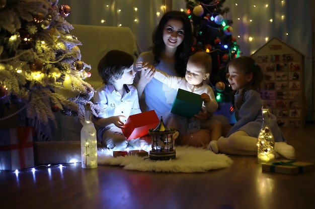 Véspera de ano novo a casa está decorada para o feriado árvore de natal elegantemente vestida com uma guirlanda e uma família com presentes e uma surpresa