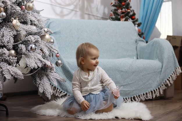 Véspera de Ano Novo. A casa está decorada para o feriado. Árvore de Natal elegantemente vestida com uma guirlanda e uma família com presentes e uma surpresa.