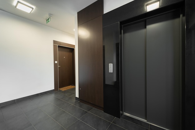 El vestíbulo del ascensor de un edificio de apartamentos moderno con paneles de madera oscura