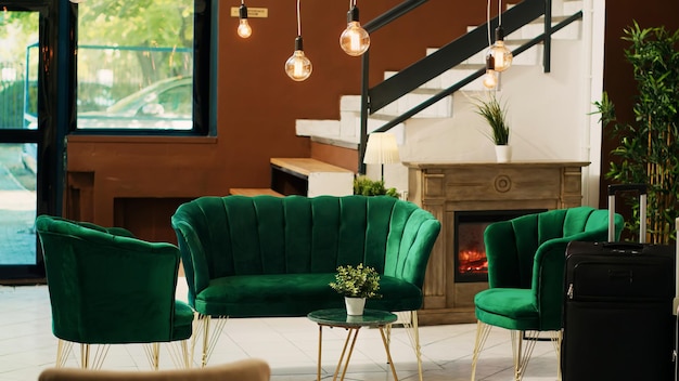 El vestíbulo del hotel con sala de estar vacía y escritorio de recepción, decoraciones y un diseño interior elegante. La entrada del complejo decorada con plantas y pisos de mármol, muebles elegantes y sofá.