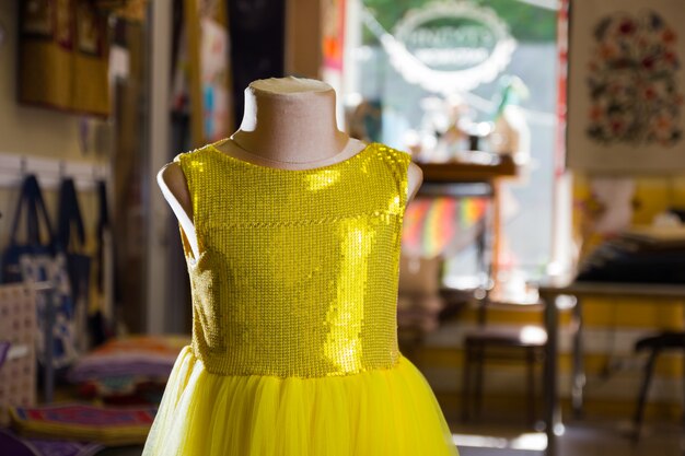 Vestido amarelo infantil com brilhos no manequim. Vestidinho amarelo no estúdio.