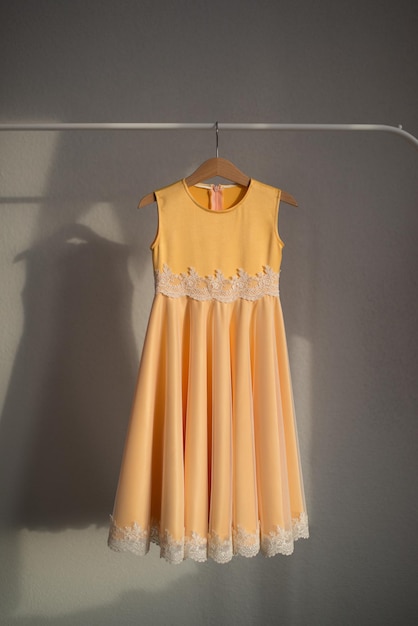 El vestido amarillo está colgado en una percha Ropa para niños