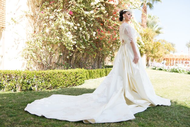 Vestido de conto de fadas. Coisas a considerar para um casamento no exterior. Noiva adorável vestido de noiva branco dia ensolarado fundo de palmeira. Ilha tropical de cerimônia de casamento. Conselhos e dicas de especialistas em casamento no exterior.