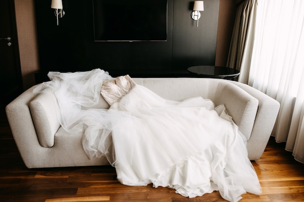 Foto vestido de noiva deitado em um sofá em quarto de hotel