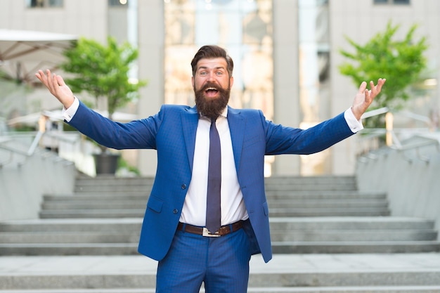 Vestido para el exito. El hombre exitoso celebra la victoria al aire libre. Celebrando el éxito profesional. Máximo logro. Cumplimiento de metas. Adelanto de la carrera. Promoción en el trabajo. Estilo de vida empresarial.