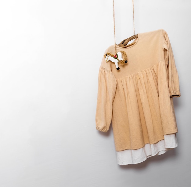 Foto vestido con juguete de caballo de madera colgado en fondo blanco de la pared concepto de moda para niños ecológicos