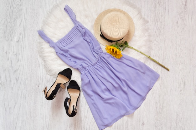 Foto vestido lila, zapatos, sombrero de paja y girasol.