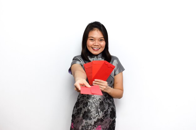 Vestido de mujer asiática Cheongsam tradicional haciendo una pose y sosteniendo un sobre rojo Angpau