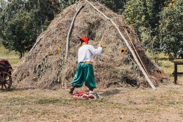 Vestido nacional ucraniano Campo de traje tradicional de homem velho Camisa bordada um homem coloca feno no palheiro Vida tradicional da aldeia na Ucrânia Campo de agricultor