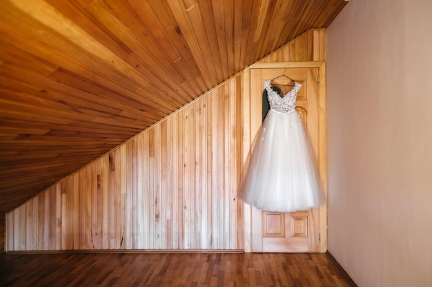 Vestido de novia colgado en la puerta sobre fondo de pared de madera