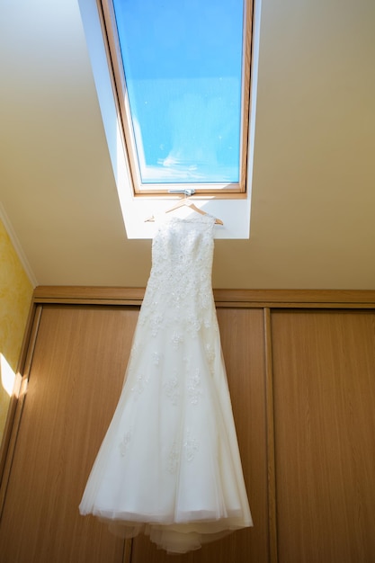 Vestido de novia colgado en la ventana de la habitación del hotel