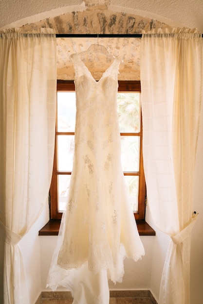 El vestido de la novia cuelga de la cornisa de la ventana.