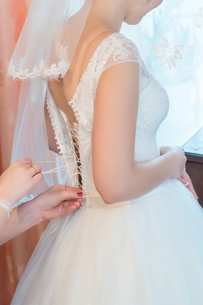 Vestido de novia de la novia en la espalda, preparación matutina para la celebración.