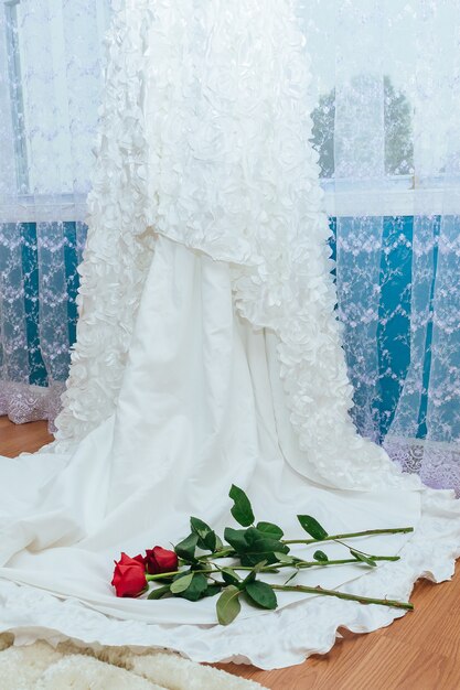 El vestido de novia perfecto con una falda completa en la habitación. Vestido de novia con rosa roja.