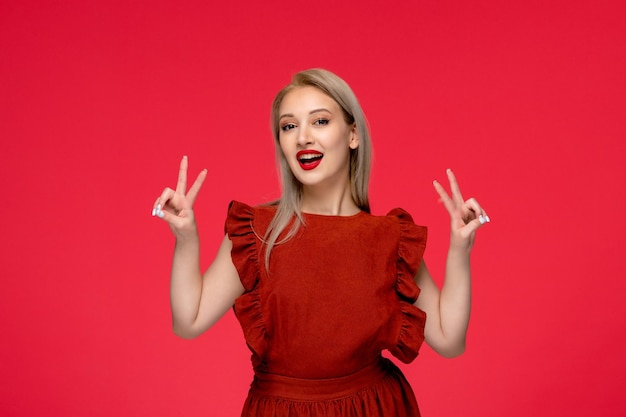 Vestido rojo elegante adorable mujer joven con vestido burdeos con lápiz labial que muestra el signo de la paz