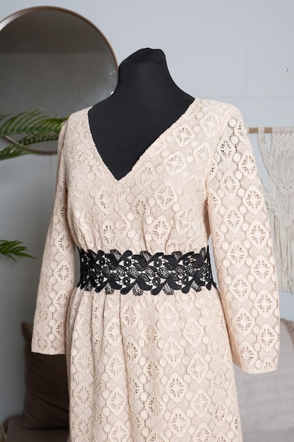 Vestido romántico de encaje beige con cinturón de encaje negro en un maniquí de sastre