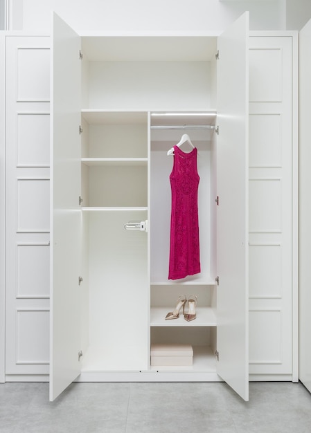 Vestido rosa y zapatos en un armario blanco vacío como parte de un interior moderno Concepto moderno de fabricación de muebles interiores