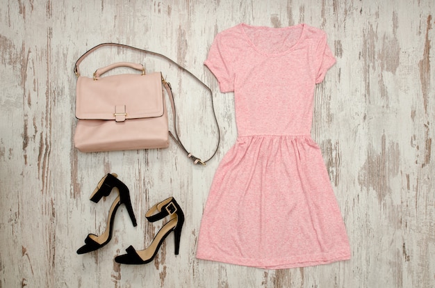 Vestido rosa con zapatos negros y bolso beige