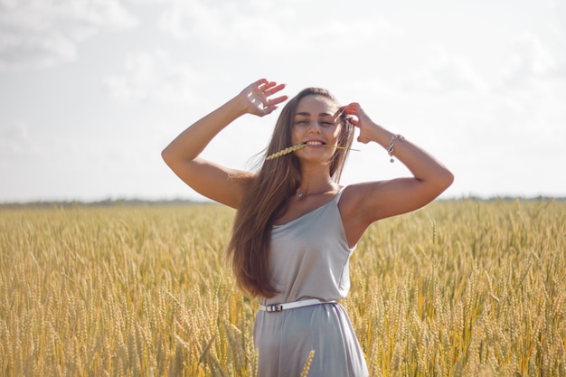 Vestido de seda plateada de cabello castaño largo de mujer de piel morena en un campo