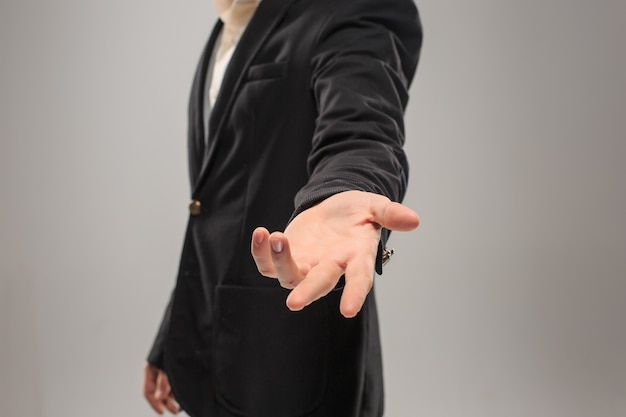 Foto vestido con un traje de negocios, gesto de la mano masculina caucásica de pedir ayuda o mostrar algo sobre el fondo oscuro