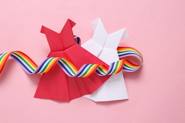 Vestidos de origami da comunidade LGBT e fita de arco-íris em fundo rosa