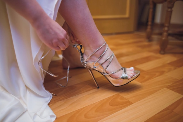 Vestidos de novia zapatos antes de la ceremonia de boda cargos de la novia primer plano detalle de novia poniendo