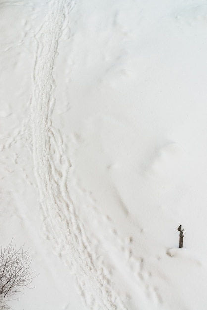 Vestígios de sapatos na neve branca. Rastreio de botas no monte de neve. Plano de fundo texturizado de inverno de trilha nevada.