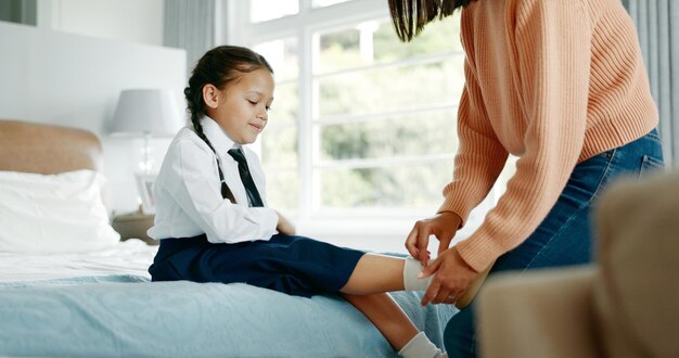 Vestimiento escolar y madre con hijo en el dormitorio preparándose para la educación aprendizaje y clases rutina matutina familiar y madre feliz con niña preparándose con uniforme de corbata y zapatos para la academia