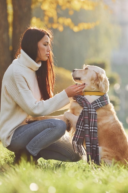 Vestindo o lenço A jovem caminha com o Golden Retriever no parque