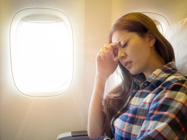 vestindo roupas de estilo casual senhora pegue o avião sentindo dor para a cabeça e a mão colocando na testa expressa desconfortável.