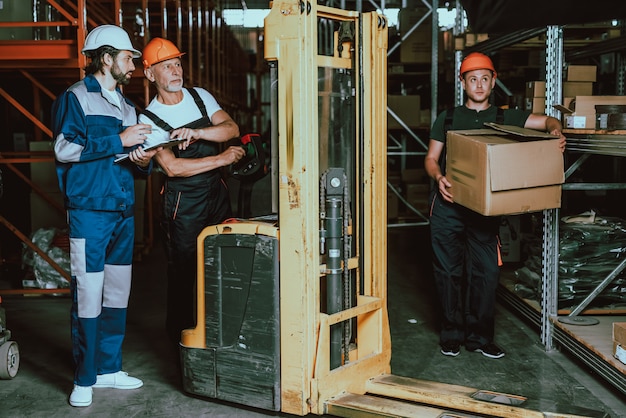 Vestindo uniforme e capacetes ao lado de empilhadeira