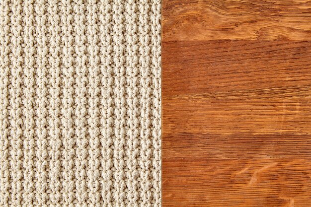 Vestuário de malha bege sobre superfície de madeira castanha Textura de fundo de lã tricotada e fundo de madeira