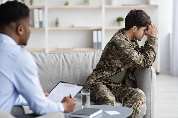 Veterano de jovem chateado atendendo psicoterapeuta na clínica