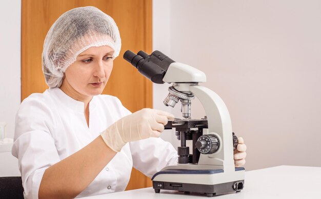 Foto veterinário científico trabalhando na pesquisa de mulheres que trabalham com microscópio em cuidados de saúde de animais de estimação e conceito de pessoas em medicina de laboratório