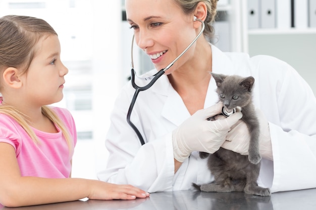 Veterinario examinando el gatito con la niña