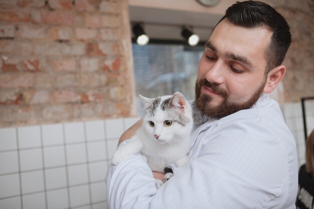 Veterinario macho con un gato en su clínica.