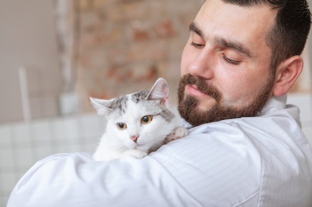 Veterinario macho con un gato en su clínica.