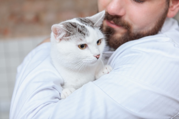 Veterinario macho con un gato en su clínica.