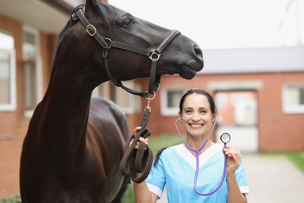Veterinario sonriente con caballo tiene estetoscopio concepto de servicios veterinarios