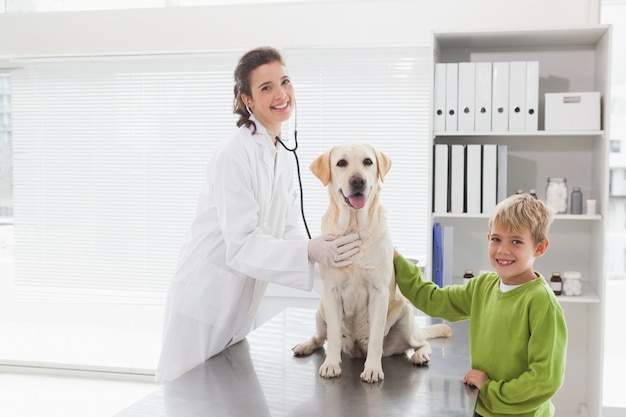 Veterinario sonriente que examina un perro con su dueño