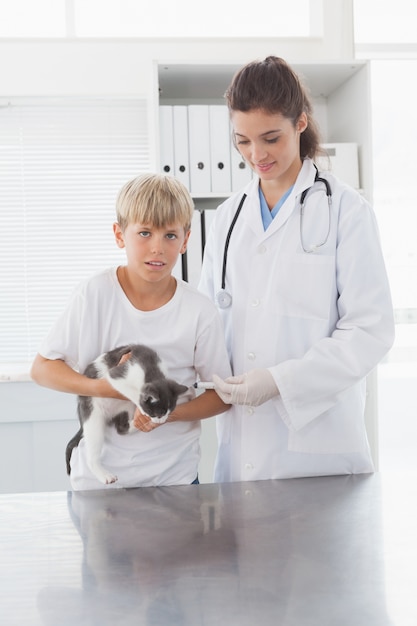 Veterinário sorrindo examinando um gato com seu dono