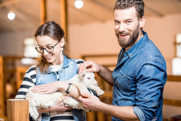 Veterinarios de hombre y mujer cuidando de cabrito en el interior del granero