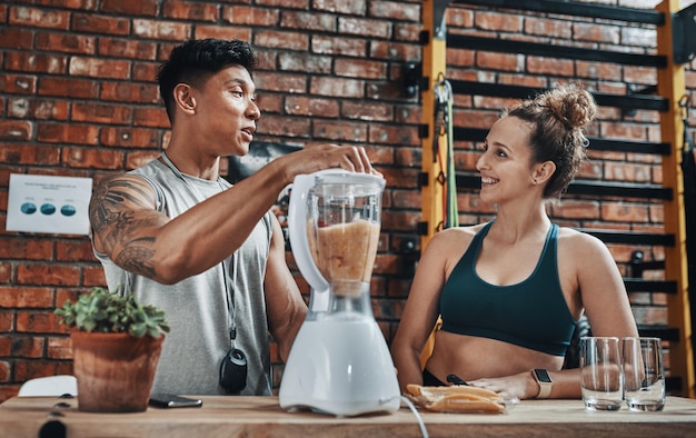 Vi esta receta en particular en un blog de dieta. Captura recortada de dos jóvenes deportistas que preparan un batido de frutas mientras trabajan en un gimnasio.