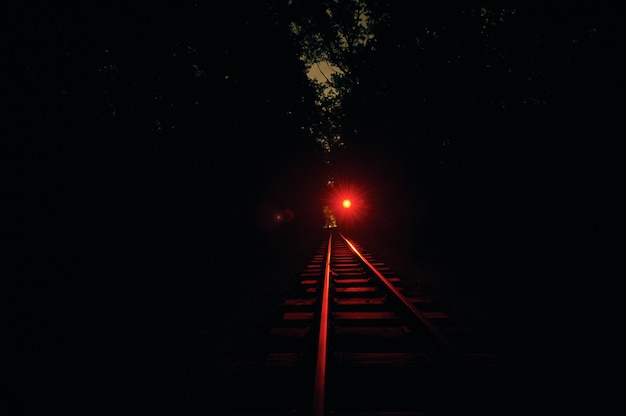 Vía férrea en la noche. La luz roja está encendida.