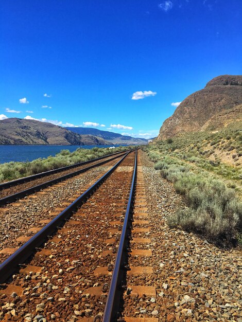 Foto la vía del ferrocarril que conduce hacia la montaña contra el cielo azul