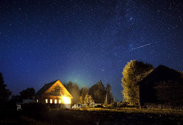 Via Láctea majestosa e a estrela cadente acima da casa da vila no verão. Um céu estrelado.