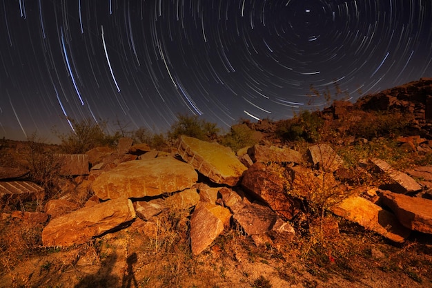 Via Láctea sobre um lago em uma pedreira de granito à noite Paisagem de verão com enormes pedregulhos árvores céu roxo com via láctea e estrelas belo reflexo na água Ucrânia Espaço e natureza