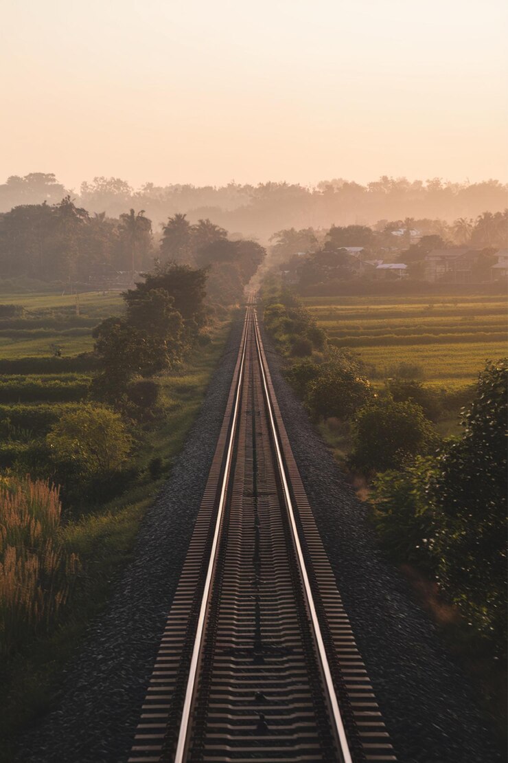 una vía de tren con un tren que atraviesa el campo